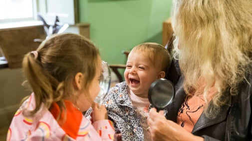 A woman and two children in the museum at Cherryburn, with a smiling baby in the centre